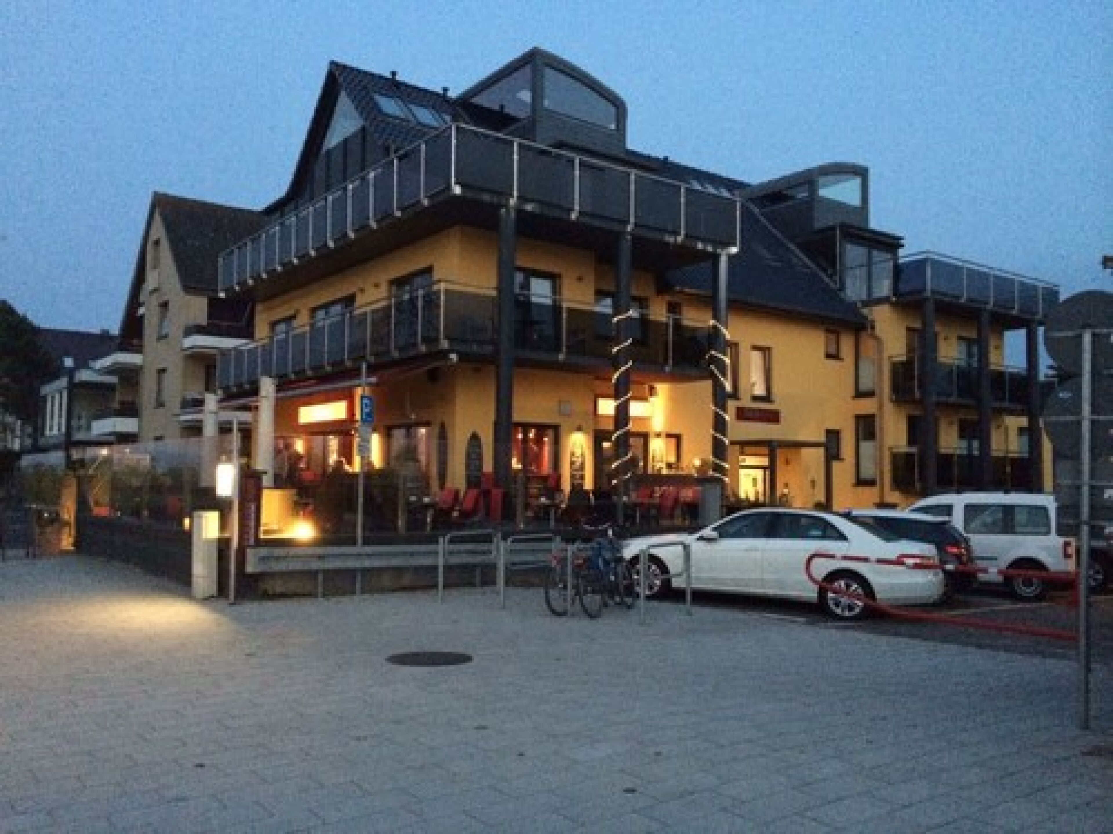 Ein mehrstöckiges Hotel mit Balkon und einem Restaurant im Erdgeschoss.