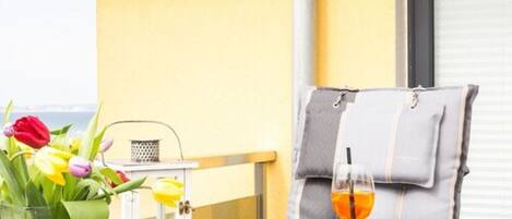 A table with a glass of orange drink, a vase with tulips, and a white lantern.