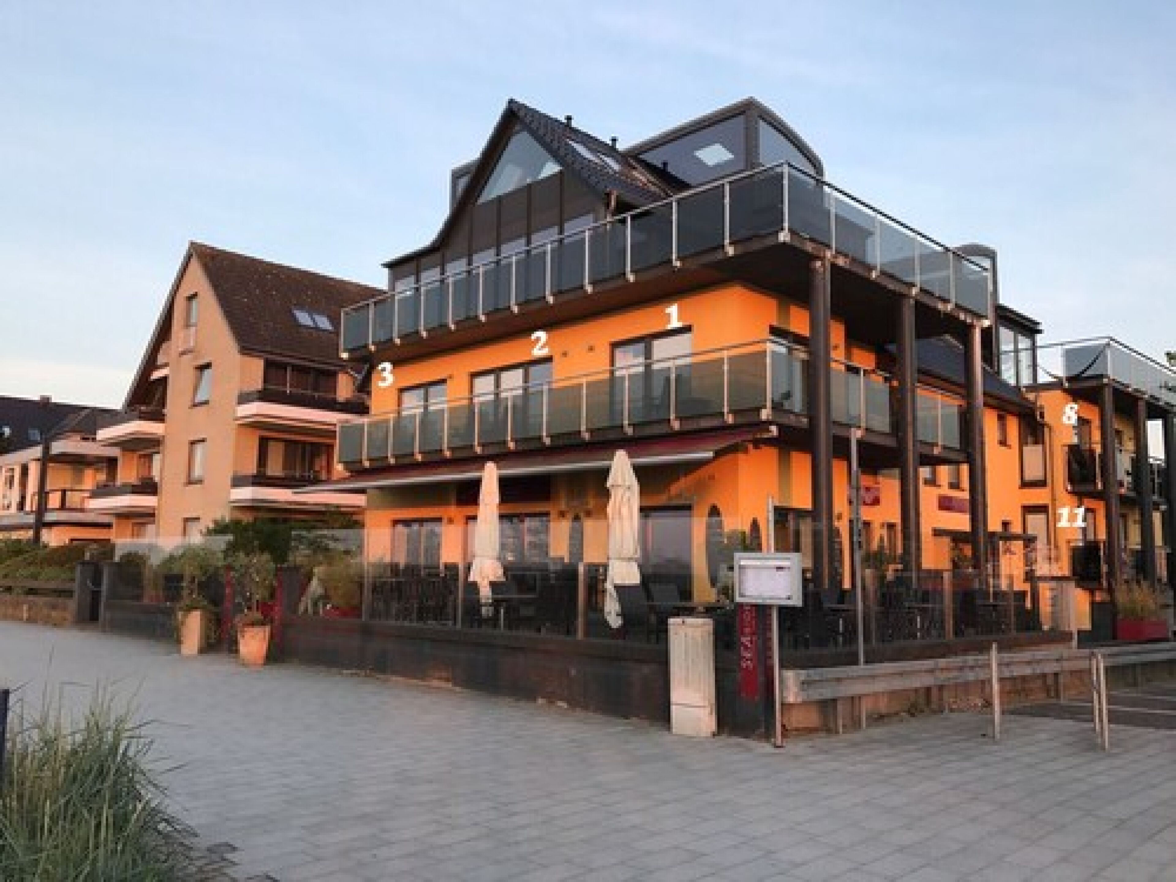 Un hôtel à plusieurs étages doté de balcons et d’un espace extérieur aménagé pour s’asseoir.