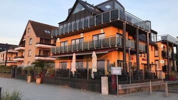 Un hôtel à plusieurs étages doté de balcons et d’un espace extérieur aménagé pour s’asseoir.