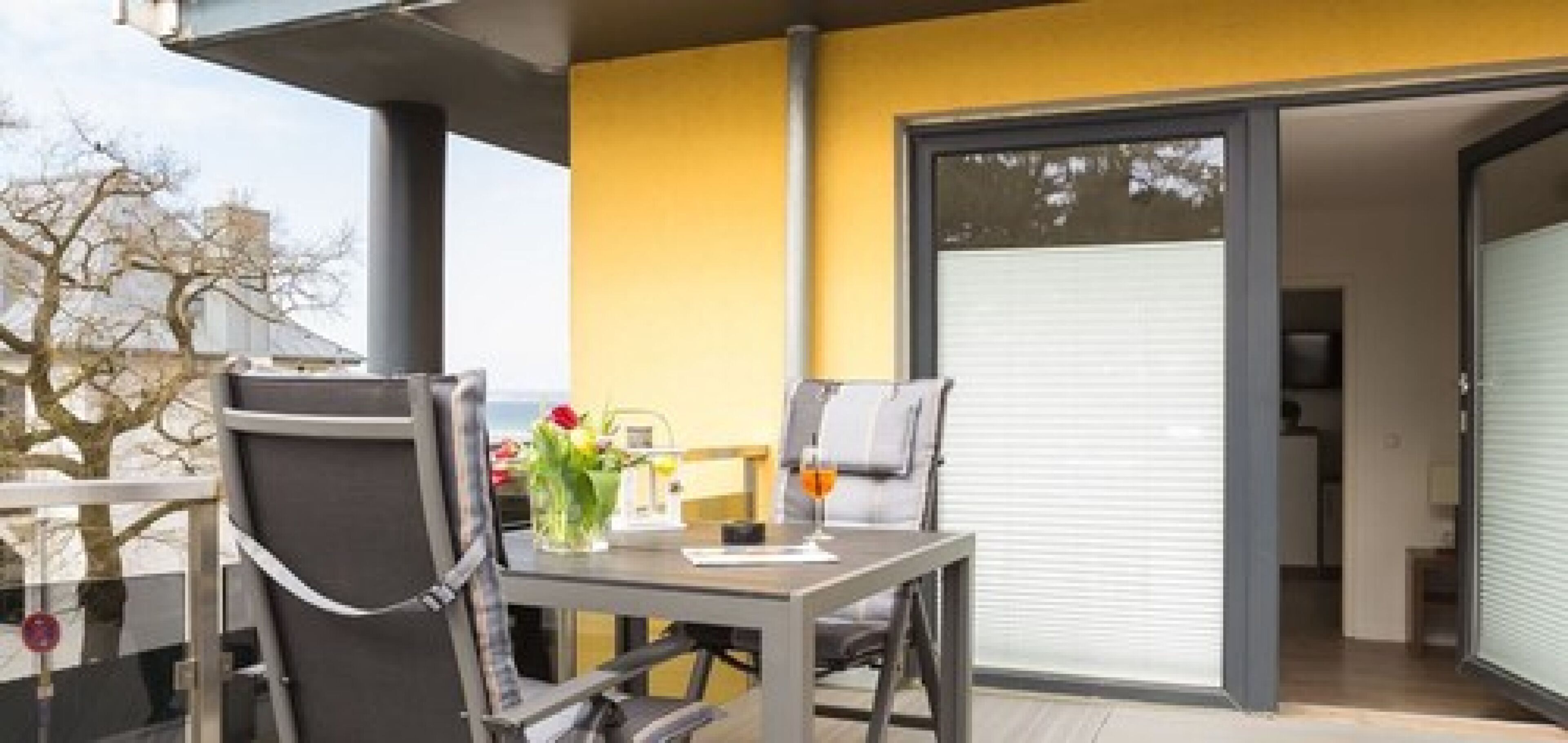Un balcon avec une table, des chaises et un verre à boire.