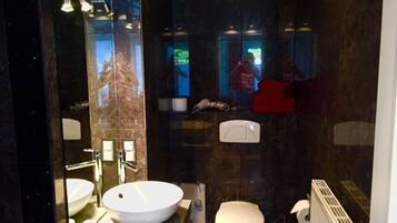 A modern bathroom with a large mirror, a round sink, a toilet, and a radiator.