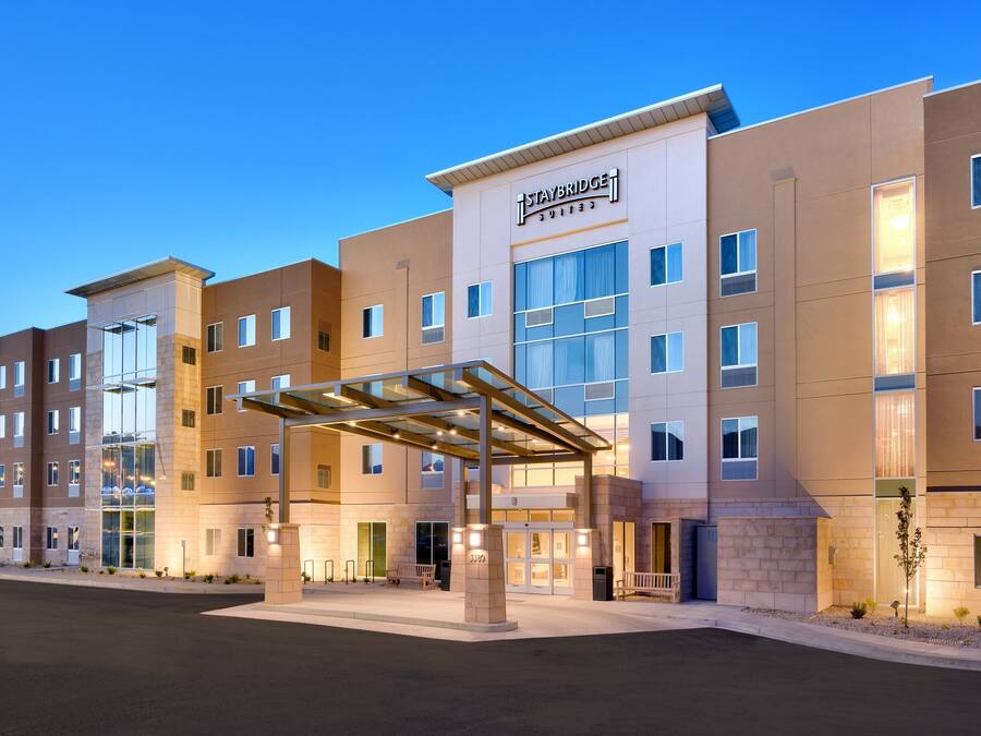 A multi-story hotel with a covered entrance, large windows, and a sign reading 'Staybridge Suites.'