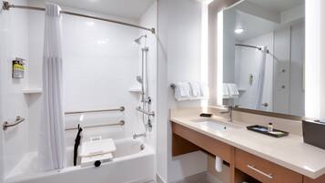 Une salle de bain moderne avec une baignoire, une douche, un meuble-lavabo et un grand miroir.