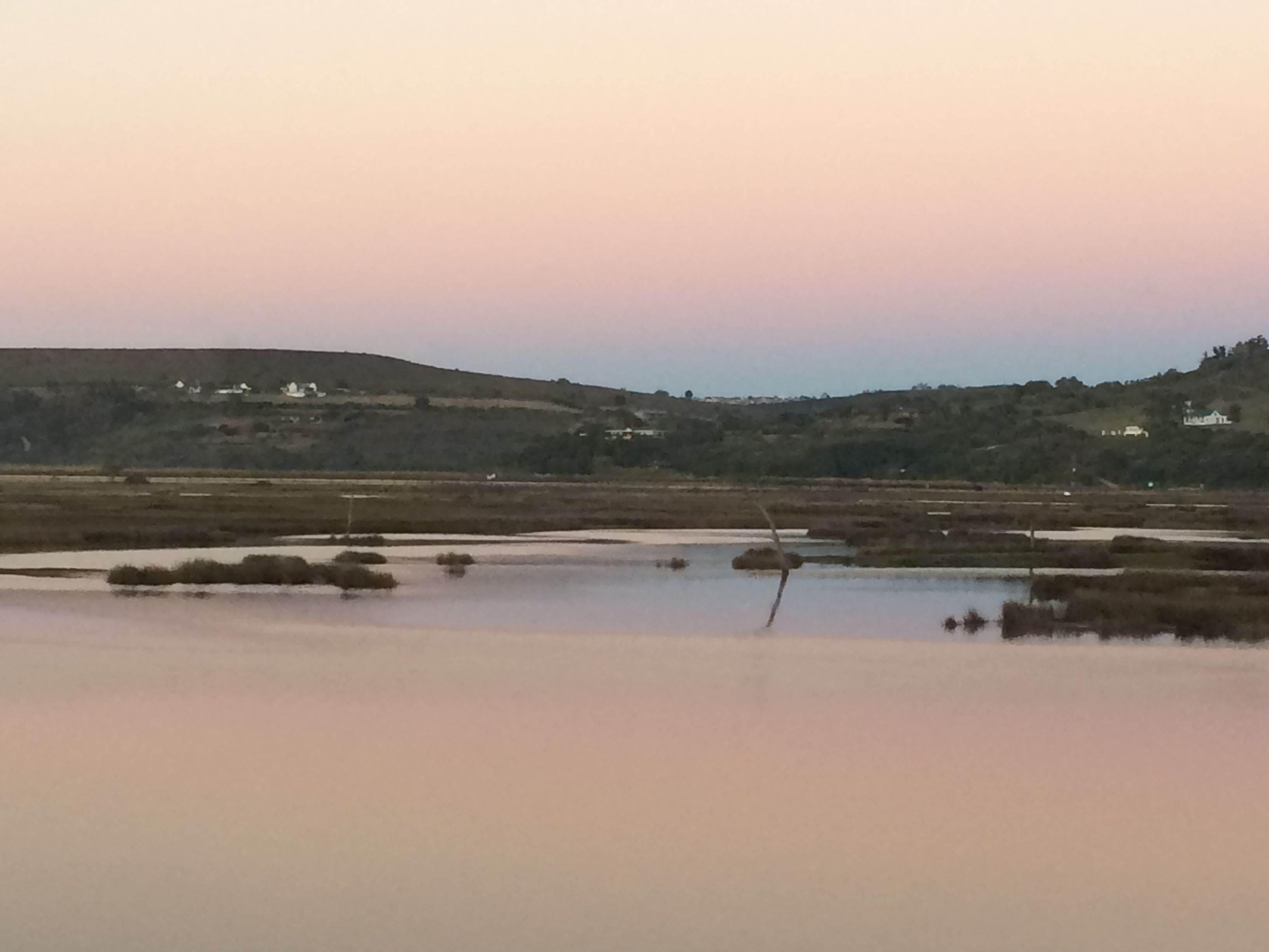 Un paysage plat, avec des étendues d’eau et des bâtiments situés au loin.