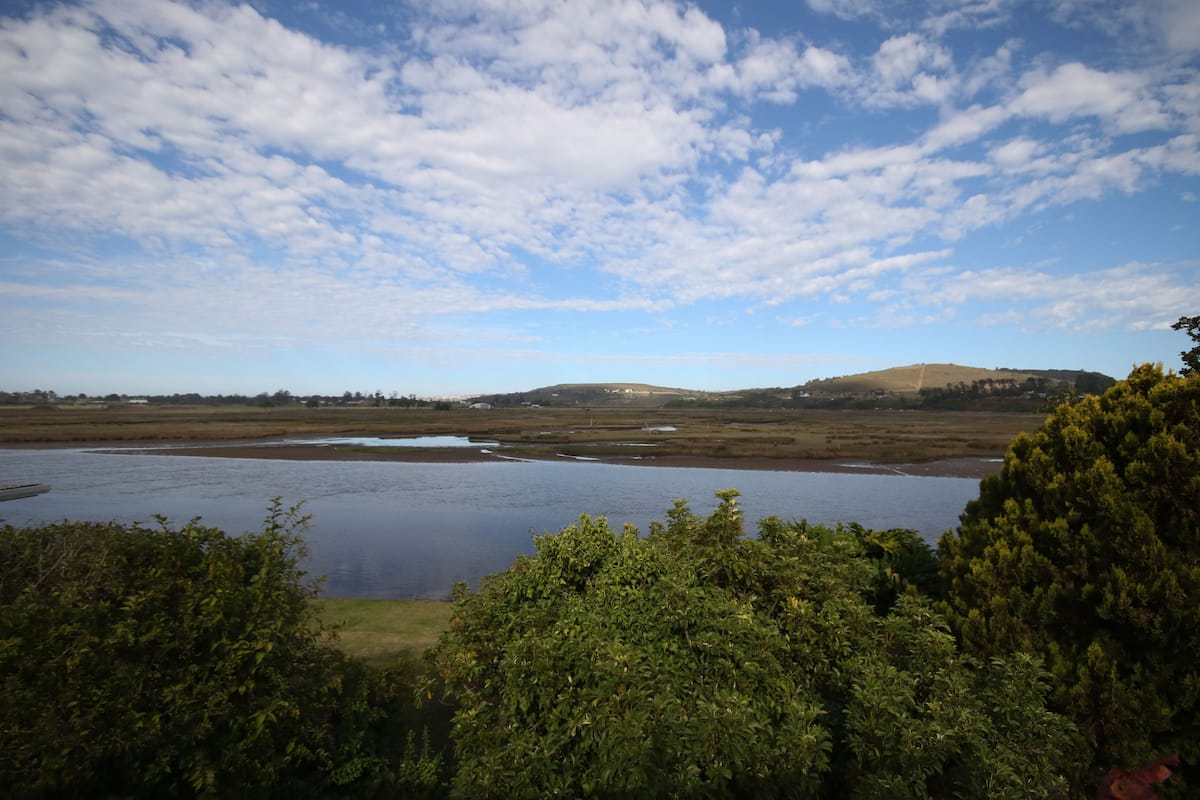A natural landscape with a body of water, hills, and dense vegetation.