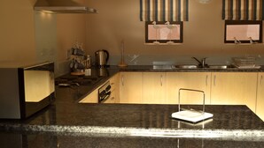 A kitchen with granite countertops, stainless steel appliances, wooden cabinets, and a window with decorative birds.