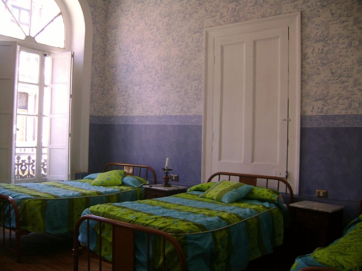 A room with two single beds, a small table, and a door.