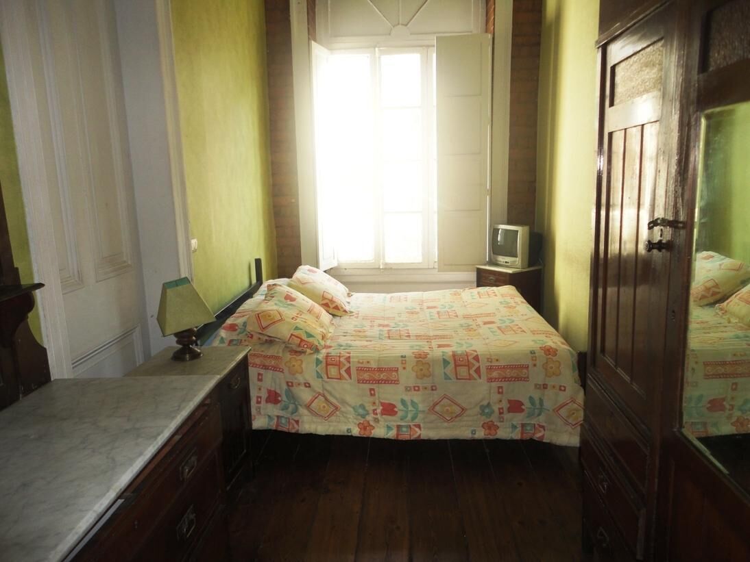 Un dormitorio con cama, mesita de noche, televisor y armario.