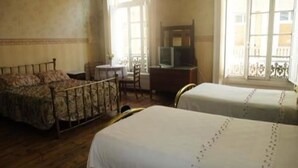 A room with two beds, a small table, a TV, and a balcony with a railing. - Hotel Garden (Valparaiso)