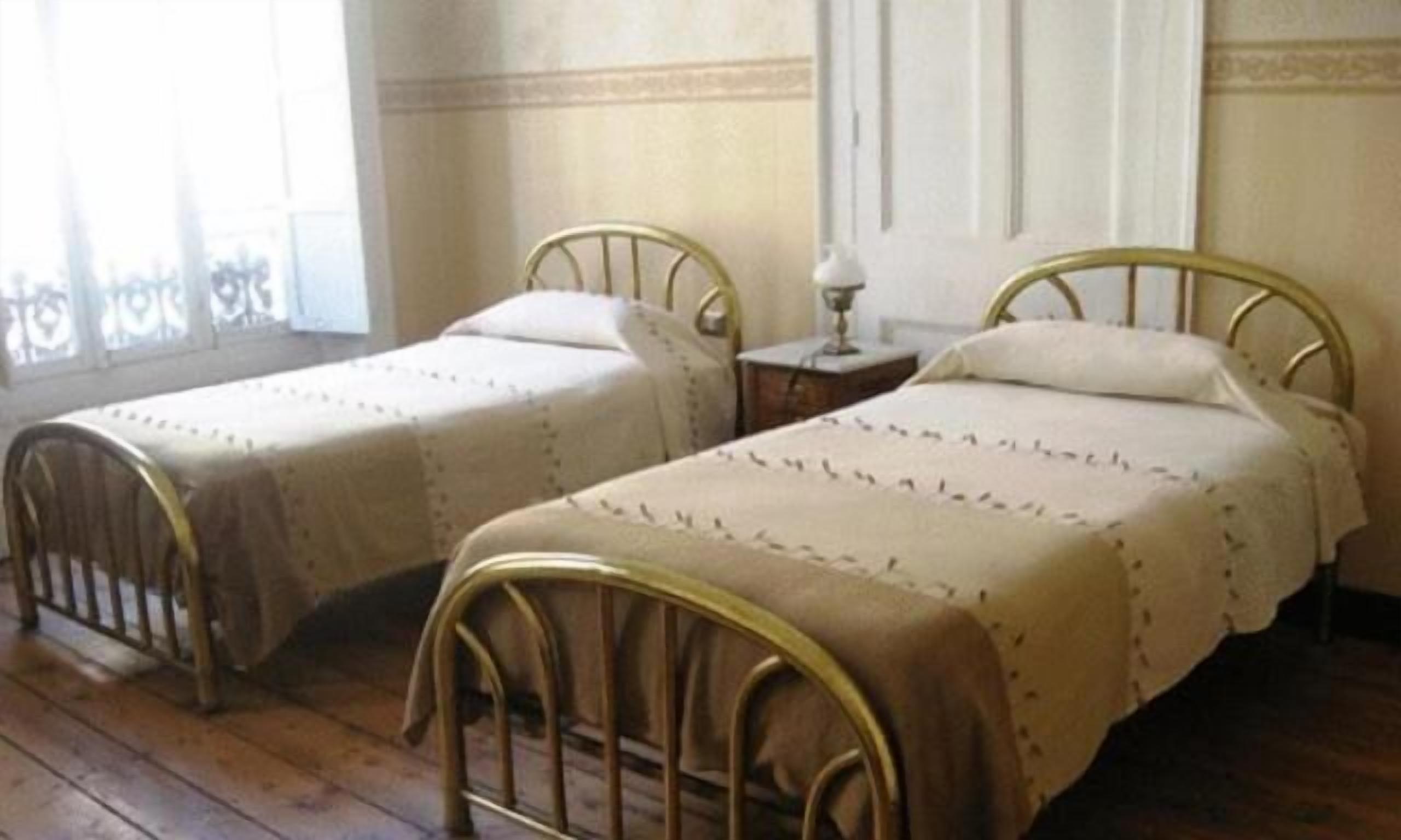 Two single beds with metal frames and wooden floors.