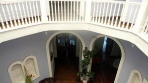 A spacious interior with a high ceiling, a balcony with white railings, and a central open area with a wooden floor. - Hotel Garden (Valparaiso)