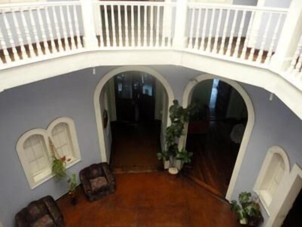 A spacious interior with a high ceiling, a balcony with white railings, and a central open area with a wooden floor.