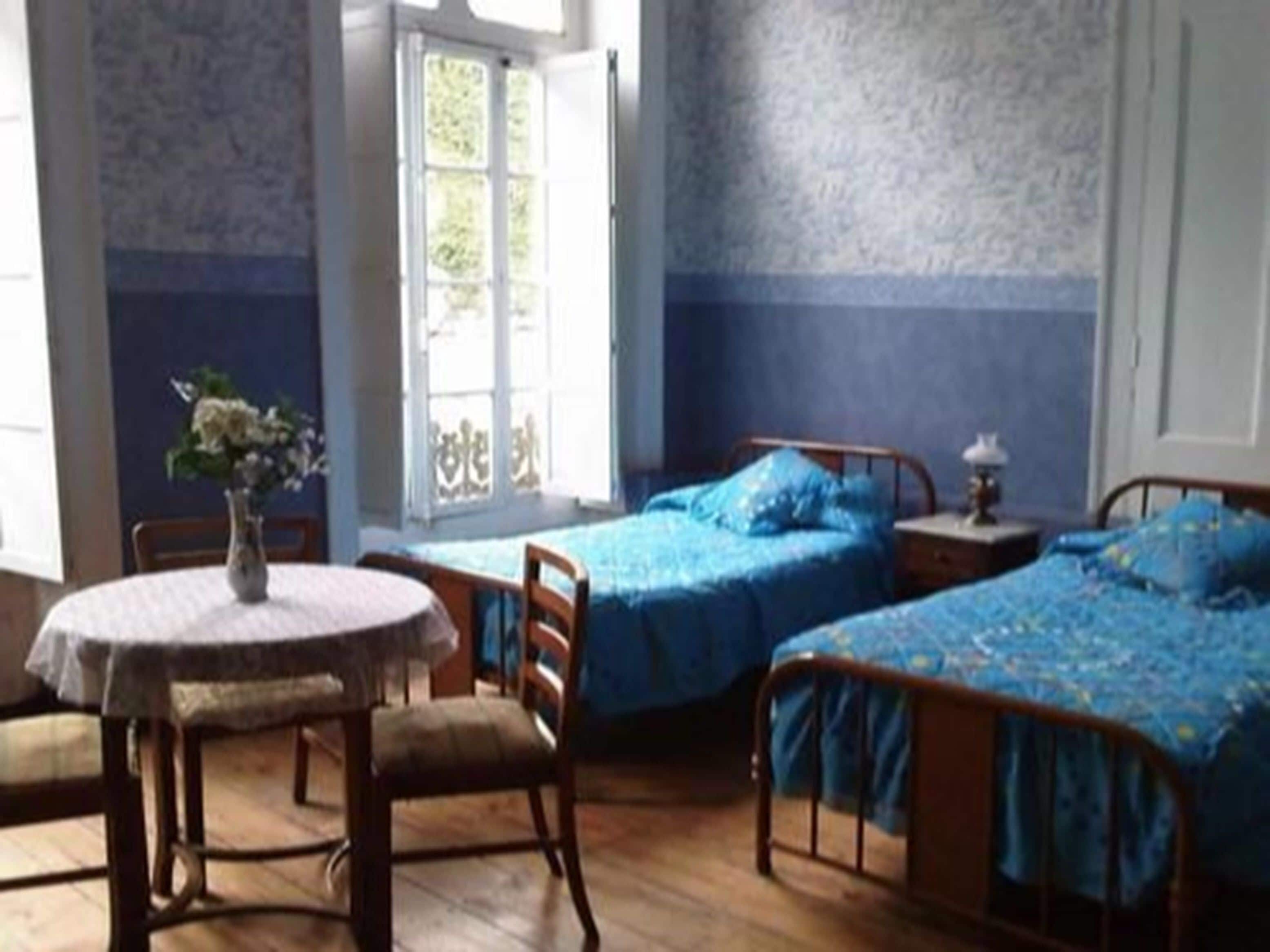A room with two beds, a round table, and chairs.
