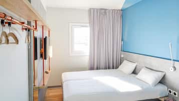 Un dormitorio moderno con cama, repisa de madera con objetos, ventana con cortinas y pared de acento azul.