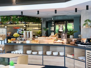 A modern cafe interior with a counter displaying pastries, a coffee machine, and a menu board.