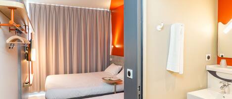 Une chambre d’hôtel avec deux lits, une salle de bain avec un lavabo et un miroir.