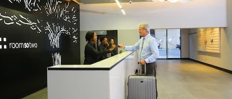 A reception desk with a modern design, a sign indicating 'room 50 two', and a view of the interior space.