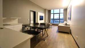 Eine moderne Wohnung mit Küche, Essbereich und einer Couch in der Nähe eines großen Fensters mit Blick auf die Stadt.