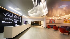 A modern reception area with a reception desk, seating area, and a large abstract artwork on the wall. - Room50two (Gaborone)