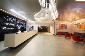 A modern reception area with a reception desk, seating area, and a large abstract artwork on the wall. - Room50two (Gaborone)