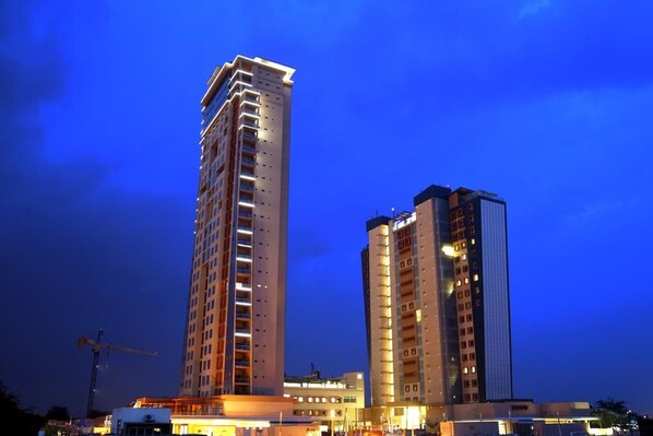A high-rise building with multiple floors, large windows, and a construction crane in the background. - Room50two (Gaborone)