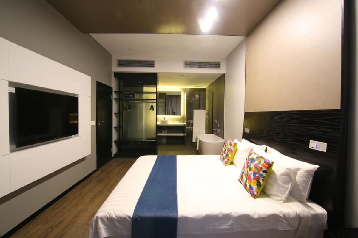 Una habitación de hotel con cama, televisor, baño y zona de ducha.