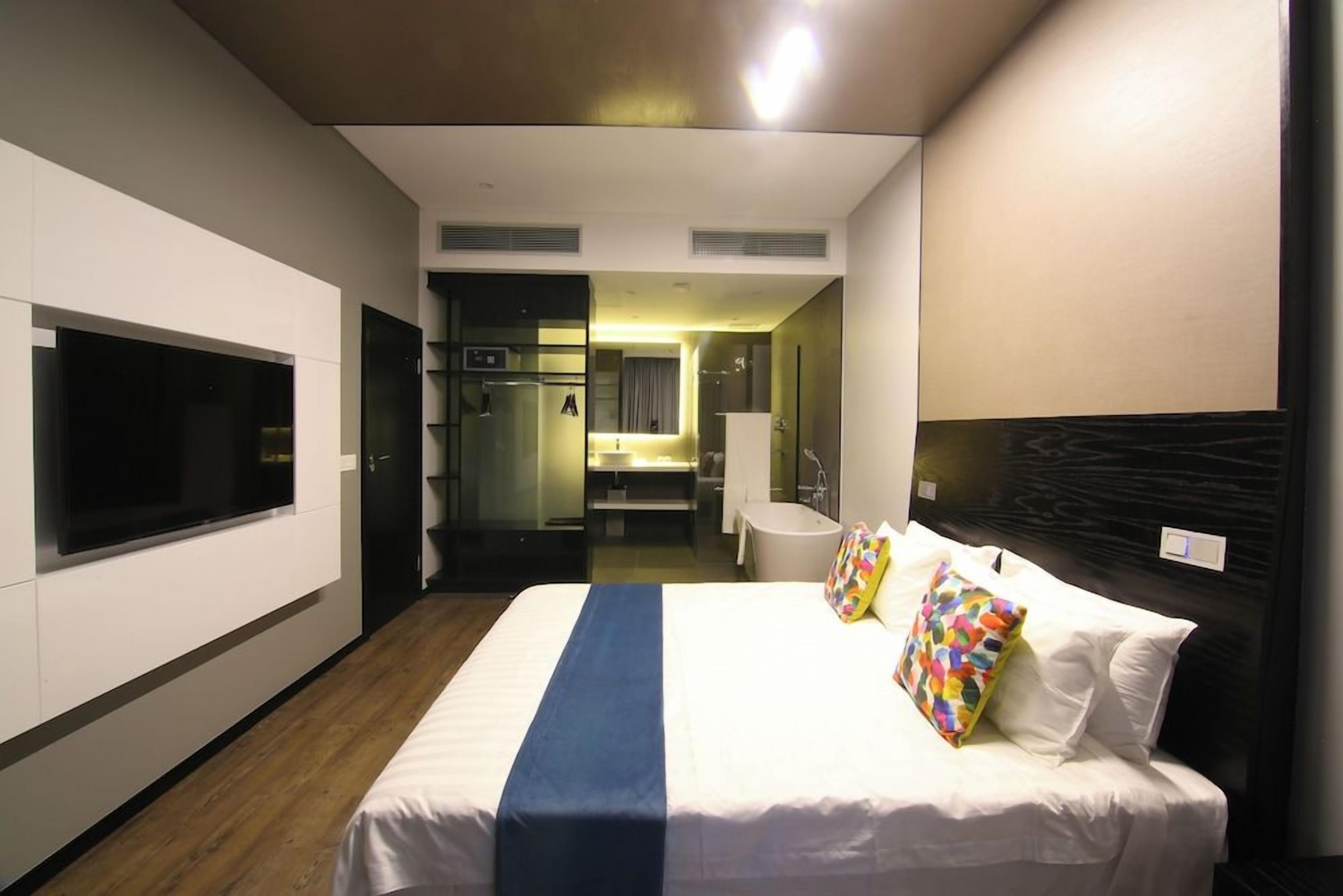 Una habitación de hotel con cama, televisión, baño y una pequeña zona de estar.