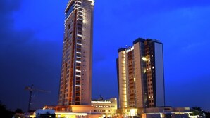 Ein Hochhaus mit zahlreichen Stockwerken, großen Fenstern und einem Baukran im Hintergrund.
