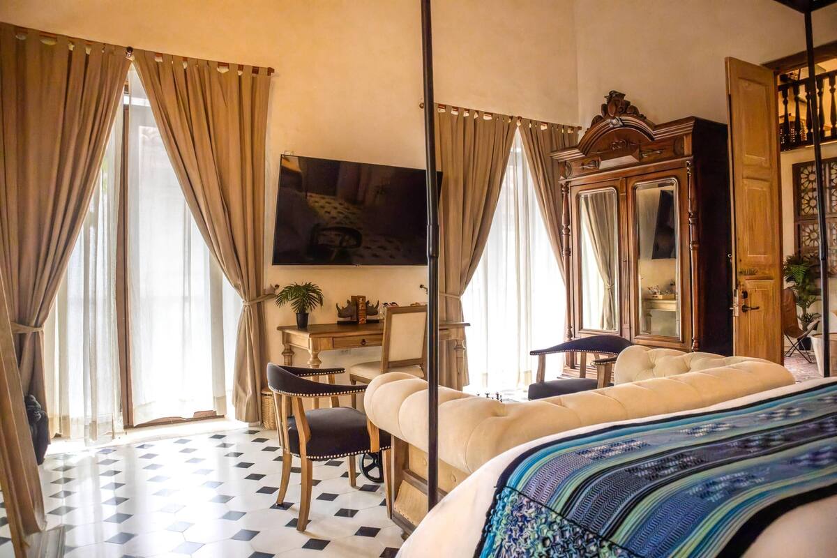 A hotel room with a bed, a desk, a chair, a television, and a wardrobe.