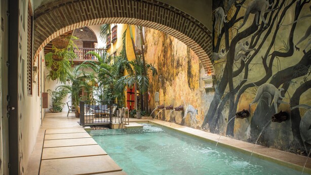 An indoor swimming pool with clear water, surrounded by a tiled walkway and a mural of monkeys on a tree. - Hotel Casa La Factoria by Faranda Boutique, a member of Radisson Individuals (Cartagena)
