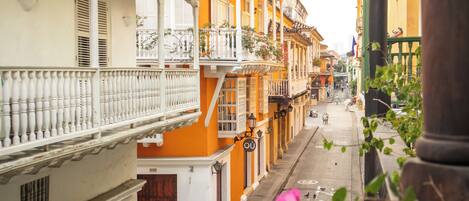A narrow street lined with colorful buildings, balconies, and a pedestrian walkway.