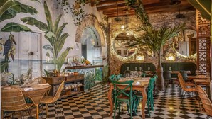 A restaurant with checkered flooring, green chairs, and a stone wall with a mirror. - Hotel Casa La Factoria by Faranda Boutique, a member of Radisson Individuals (Cartagena)