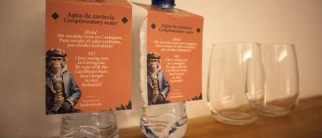 Two bottles of water with labels and two empty glasses on a wooden surface.