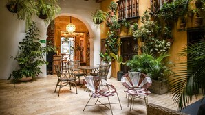 An indoor courtyard with wicker chairs, potted plants, and a wooden staircase. - Hotel Casa La Factoria by Faranda Boutique, a member of Radisson Individuals (Cartagena)