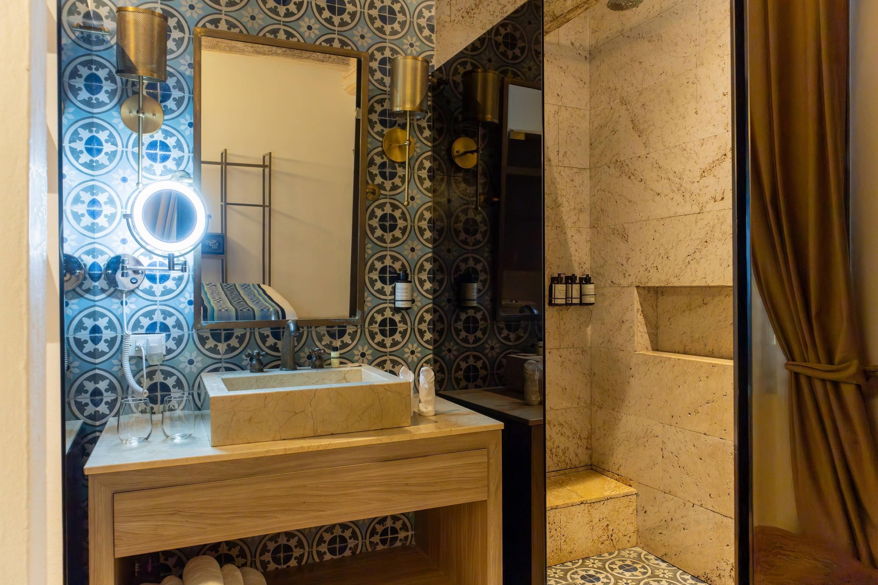 A bathroom with a sink, mirror, and patterned tiles.