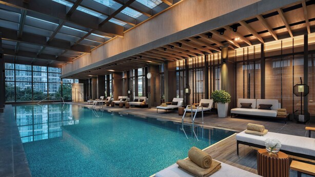 Een binnenzwembad met loungegedeeltes, grote ramen en een modern architectonisch ontwerp.