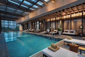 Une piscine intérieure dotée d’espaces de détente, de grandes fenêtres et d’une architecture moderne.