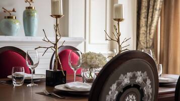 A dining table set with plates, glasses, and a vase of flowers.