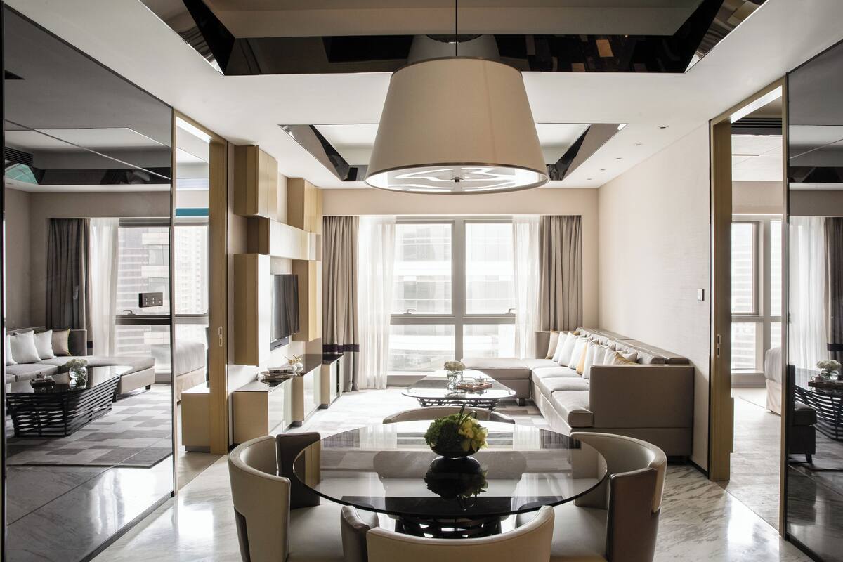 Habitació d'hotel moderna amb una gran taula de dinar, seients còmodes i grans finestres amb vistes a la ciutat.