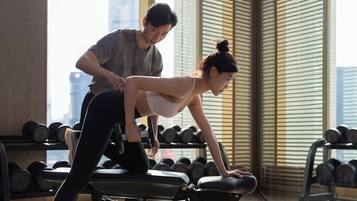 A gym with exercise equipment and a person performing a stretching exercise.