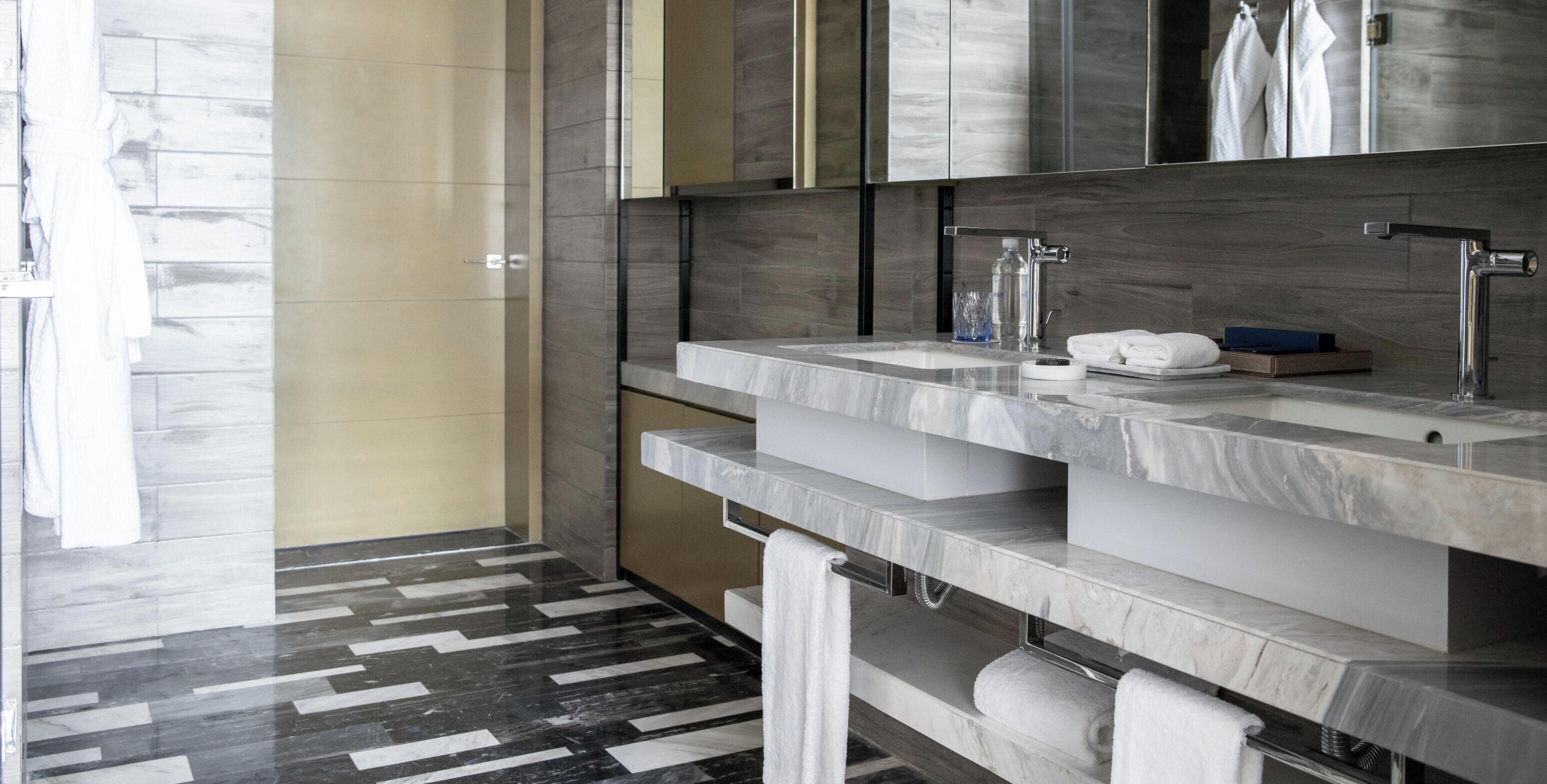 Un baño moderno con dos lavamanos, un espejo grande y un piso con diseño.