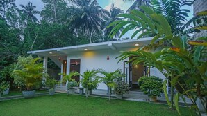 A modern house with a white exterior, a well-maintained lawn, and various potted plants. - Saku Residence (Unawatuna)