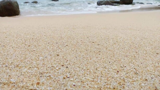 A sandy beach with large rocks and waves in the background. - Saku Residence (Unawatuna)