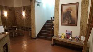 A lobby with a staircase, a reception desk, a fireplace, and a wall with a framed painting. - Hotel Refugio del Inca (Salta)