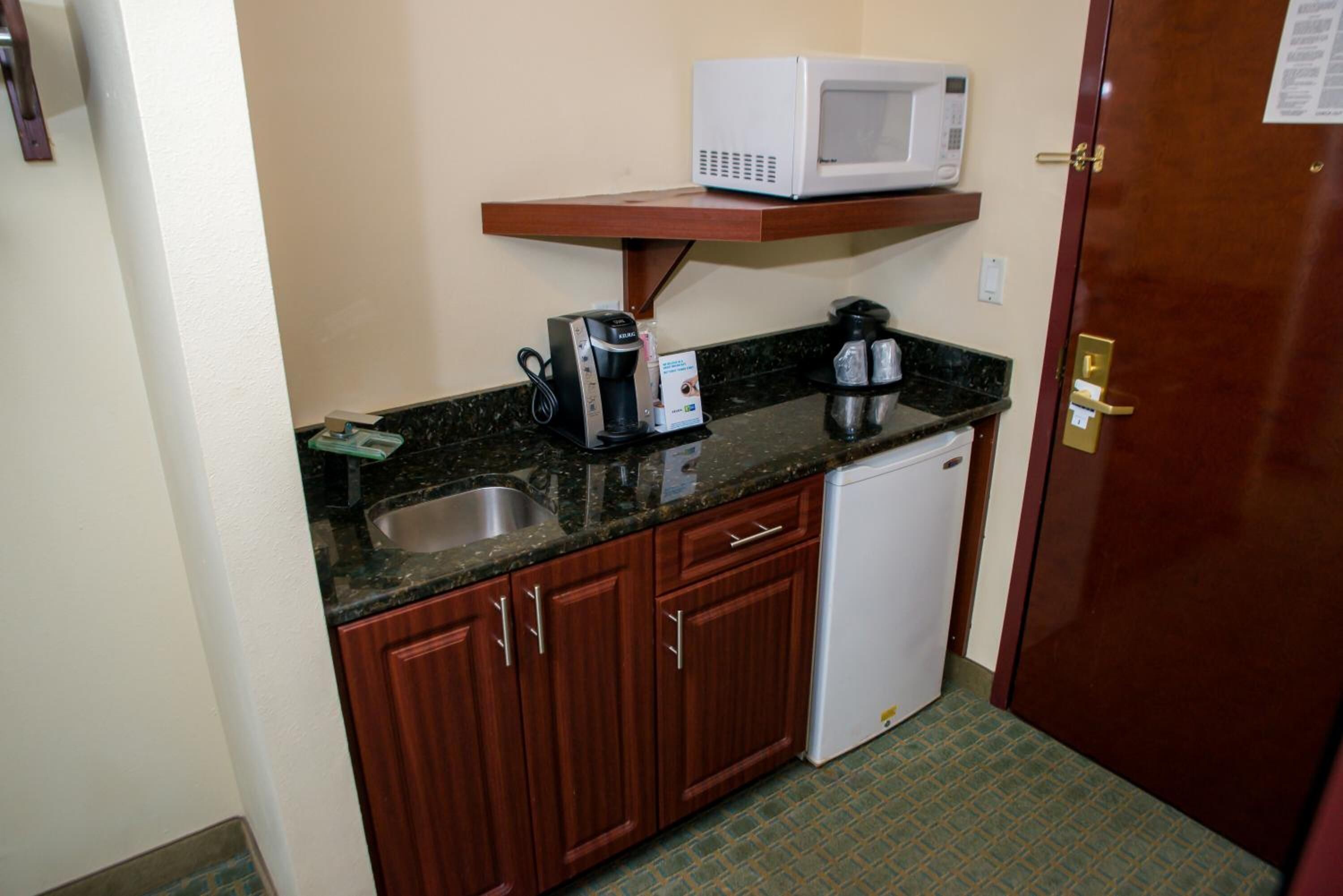 A compact kitchenette with a microwave, coffee maker, and a small refrigerator.