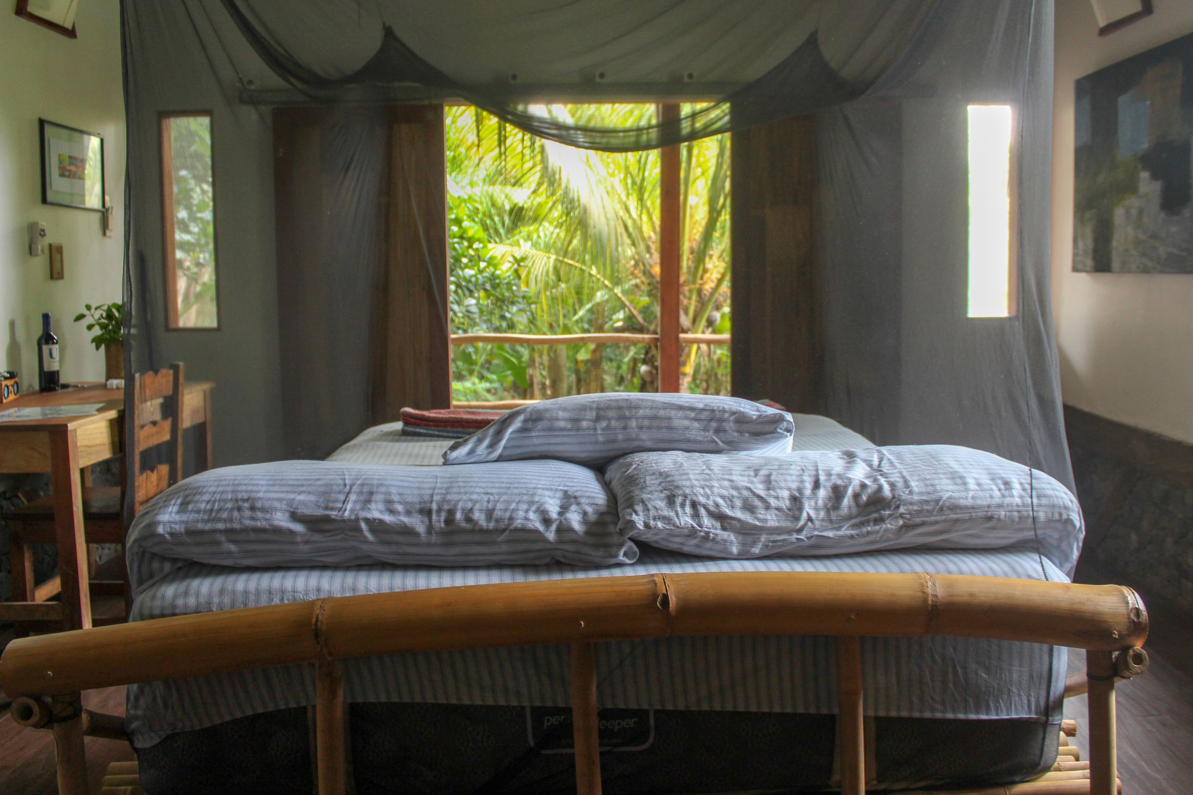 Een kamer met een bed, een bureau en een raam met gordijnen.