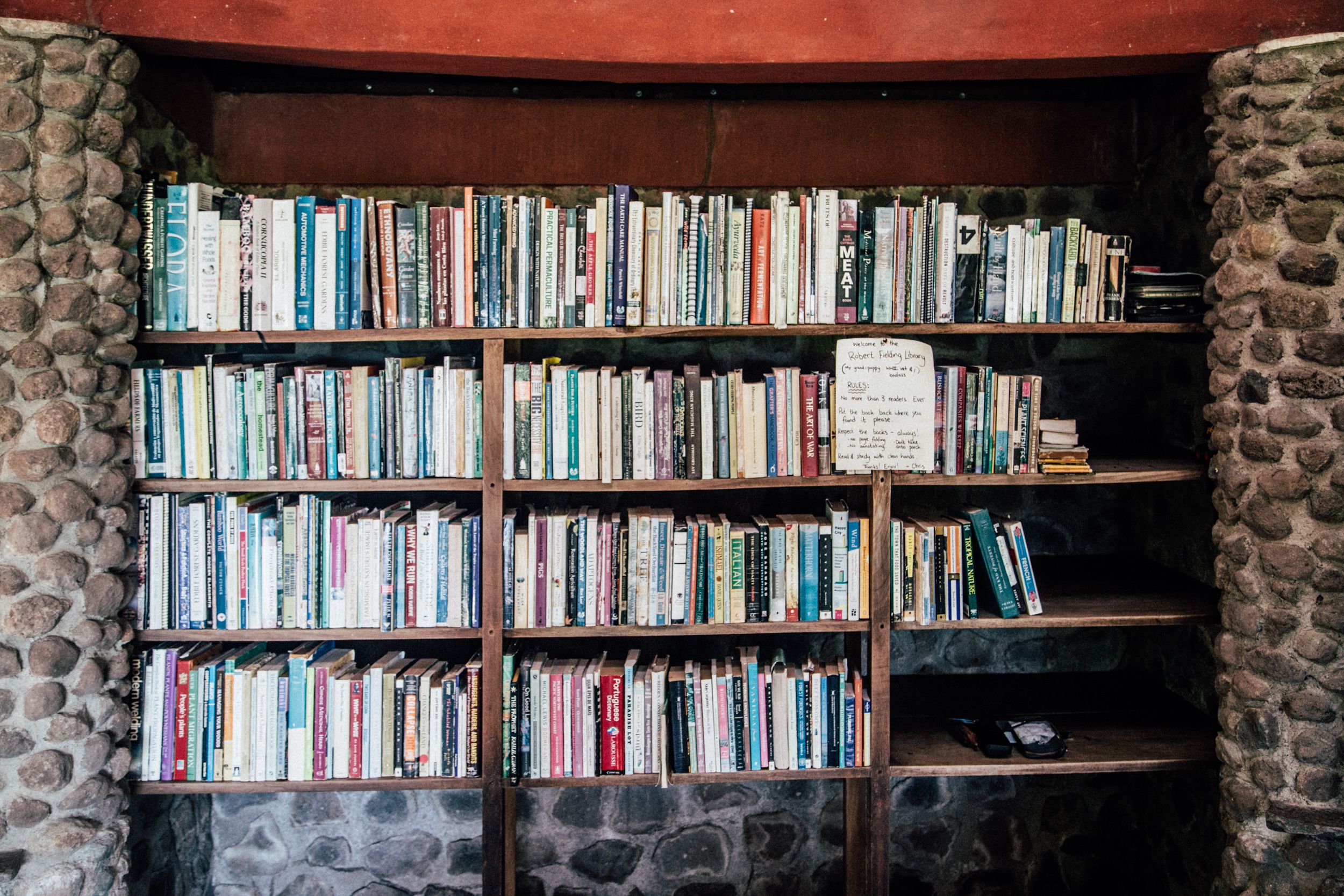 A bookshelf filled with books, set against a stone wall.