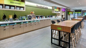 Un ristorante moderno con un lungo bancone, diverse opzioni di posti a sedere e una varietà di distributori di cibo e bevande.