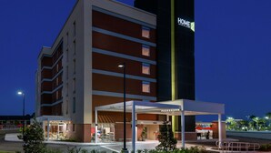 Un hotel moderno con un'insegna ben visibile con la scritta 'HOME', diversi piani e un'area d'ingresso coperta.